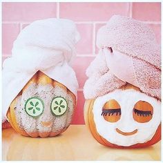 two pumpkins with faces painted to look like they are wearing towels on their heads