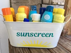 a bucket filled with sunscreen on top of a wooden bench