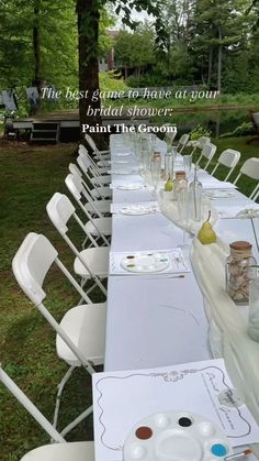 a long table is set up with white chairs and place settings for the guests to eat