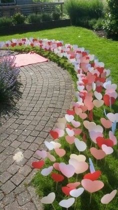 some pink and red flowers are in the middle of a brick path with green grass