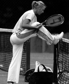 black and white photograph of a tennis player leaning on the net with her racket