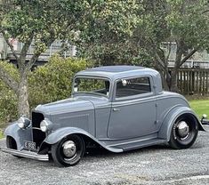 an old gray car parked in a parking lot