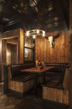 the interior of a restaurant with wood paneling and cow heads on the wall, along with leather booths