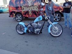 a man standing next to a motorcycle parked in front of a van with flames on it