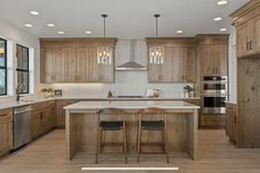 a large kitchen with wooden cabinets and an island in the middle, along with two bar stools