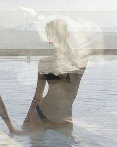 a woman is sitting in the water with her back to the camera