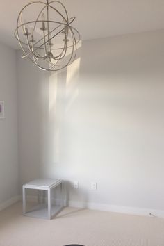 an empty room with a round light fixture hanging from the ceiling and a small table in front of it