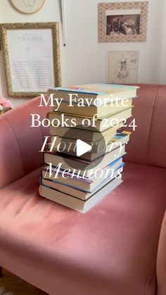 a stack of books sitting on top of a pink couch