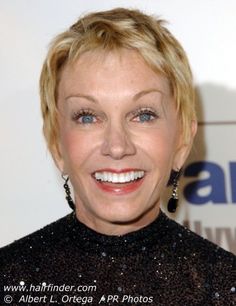 an older woman with blonde hair and blue eyes smiles at the camera while wearing black