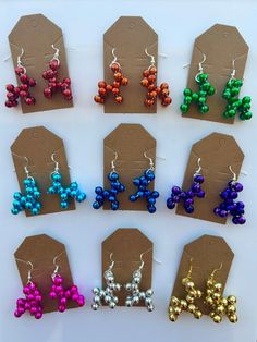 six pairs of earrings with different colors and shapes are shown in front of a brown tag