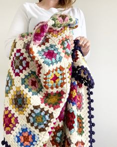 a woman is holding a crocheted blanket