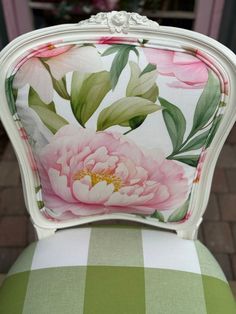 an upholstered chair with pink flowers on the back and green checkered seat