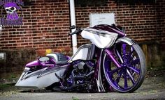 a purple and white motorcycle parked on the side of a road next to a brick building