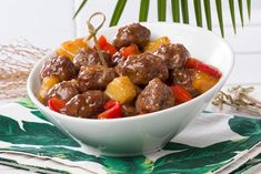 a white bowl filled with meat and veggies on top of a green napkin