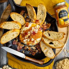 a plate with bread, jam and bacon on it next to two bowls of crackers