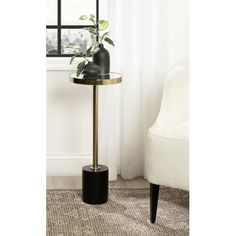 a black and gold side table with a potted plant on it in front of a window