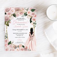 a pink and white floral bridal gown wedding card on top of a table next to a candle