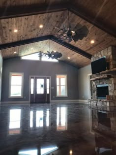 an empty room with a ceiling fan and large windows in the center is lit by recessed lights