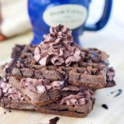 three pieces of chocolate cake sitting on top of a wooden cutting board next to a blue mug