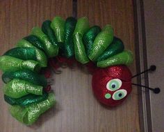 a very cute green and red wreath made to look like a caterpillar with googly eyes