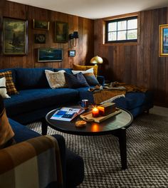 a living room with wood paneling and blue couches, coffee table in the middle