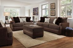 a living room with couches, chairs and ottomans in front of two windows