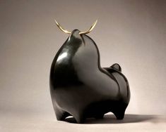 a black sculpture with gold horns on it's head and back end, sitting in front of a gray background