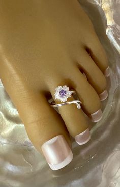 This silver toe ring features a a brilliant silver flower that cups up and has a purple crystal accent in the center . This toe ring is size adjustable and one size fits most. Comfortable and versatile, it will lend itself to casual or formal events. All items are made in a smoke free environment. *If there is any issue with your toe ring, please let me know so I can correct it. Thanks for visiting my shop!👣 Silver Flower Ring With Birthstone, Purple Flower Ring For Anniversary, Adjustable Silver Toe Ring With Flower Design, Silver Flower Toe Ring, Toe Ring Designs, Sterling Silver Toe Rings, Silver Toe Rings, Purple Crystals, Toe Rings