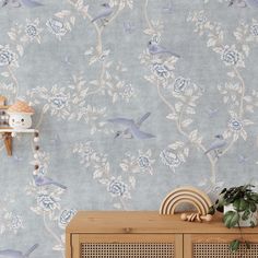 a blue wallpaper with birds and flowers on it, next to a wooden cabinet