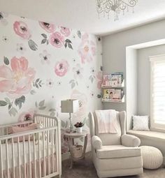 a baby's room decorated in pink and gray with flowers on the wall, crib, rocking chair, window, and lamp