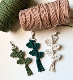 three crocheted shamrocks and two spools of thread on a white surface