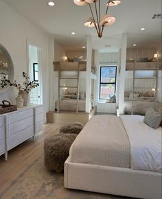 a large white bedroom with bunk beds in the corner and lights hanging from the ceiling