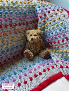 a teddy bear sitting on top of a crocheted blanket