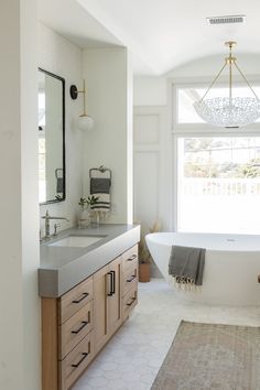 a bathroom with a tub, sink and large mirror in it's center area