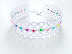 a white tiara with multicolored beads on the front and sides, sitting on a white surface