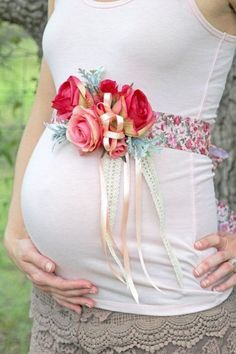 a pregnant woman wearing a flower belt with flowers on it's waist and holding her belly