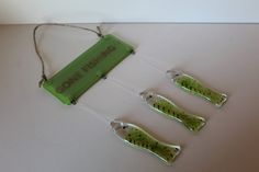 three plastic fishing lures are hanging from a string on a white counter top with the words gone fishing written on it