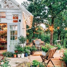 an outdoor patio with potted plants and lights strung from the roof, surrounded by greenery