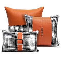 three black and white pillows with orange trims on each pillow, one has a zippered closure