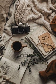 an open book, coffee cup and camera on a bed