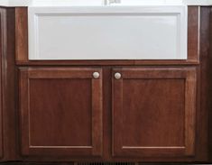 a white sink sitting under a kitchen window next to a wooden cabinet and counter top