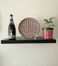 a black and white plate sitting on top of a shelf next to a red vase