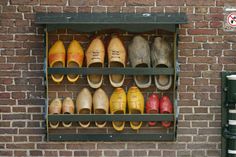 several pairs of shoes are lined up on a shelf in front of a brick wall