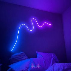 a purple light is shining on the wall above a bed