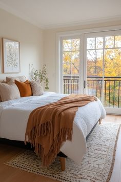 a bedroom with a large bed and wooden flooring next to a sliding glass door