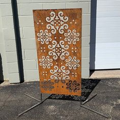 a wooden sign sitting on top of a metal stand next to a white brick wall