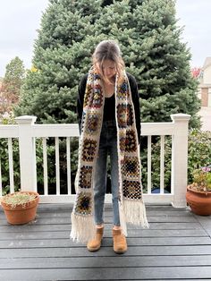 a woman standing on a porch wearing a scarf