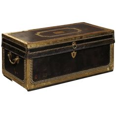 an antique leather trunk with gold trimmings on the top and bottom, sitting against a white background