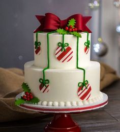 a three tiered christmas cake decorated with holly and candy canes on a wooden table