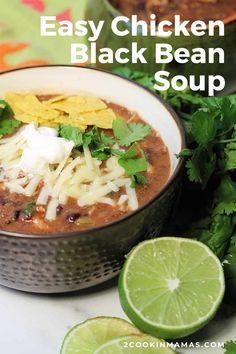 a close up of a bowl of black bean soup with cilantro and lime